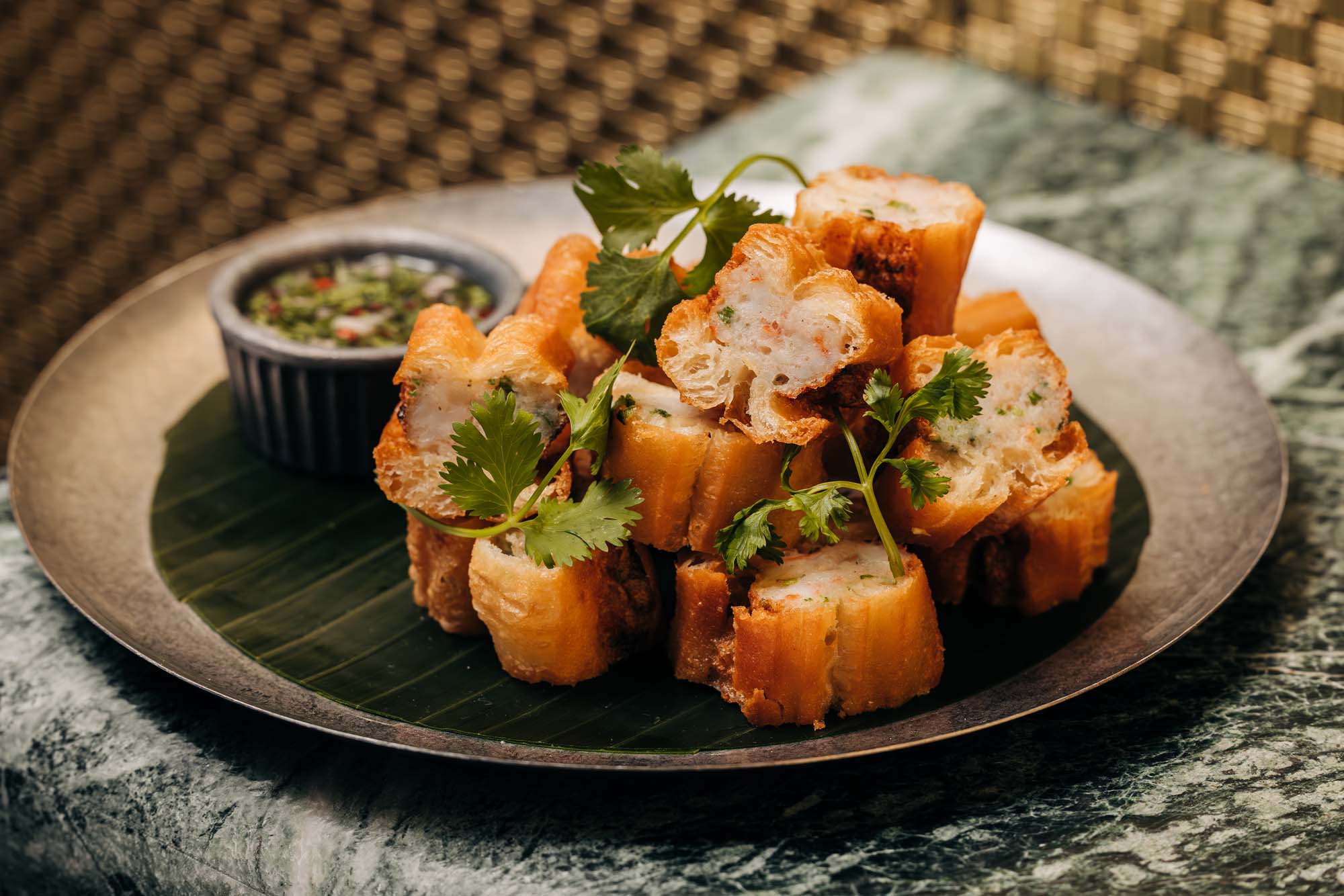Crying Tiger prawn toast with fresh herbs, photographed on green marble